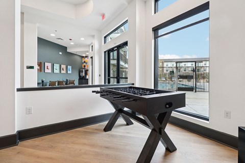 A black pool table in a room with a view of the outside.
