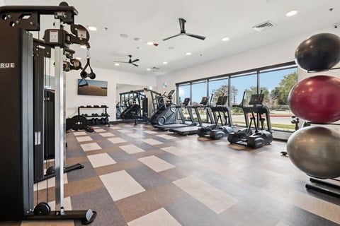 A gym with a variety of equipment including a weight machine, a treadmill, and a rowing machine.