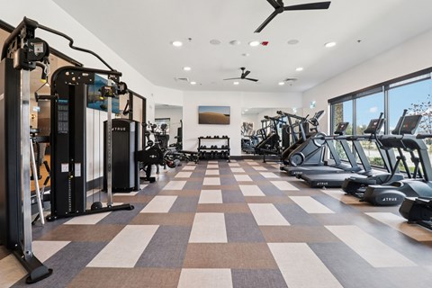 A gym with a variety of equipment including treadmills, stationary bikes, and weight machines.