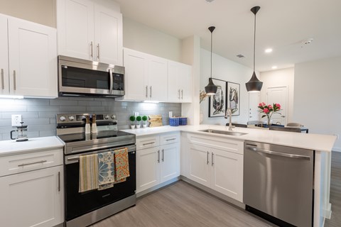 A modern kitchen with white cabinets and stainless steel appliances.
