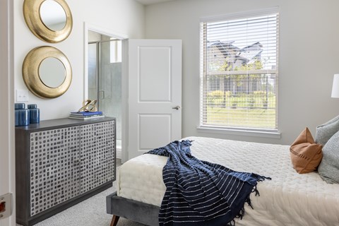A bedroom with a bed, a dresser, and two round mirrors on the wall.