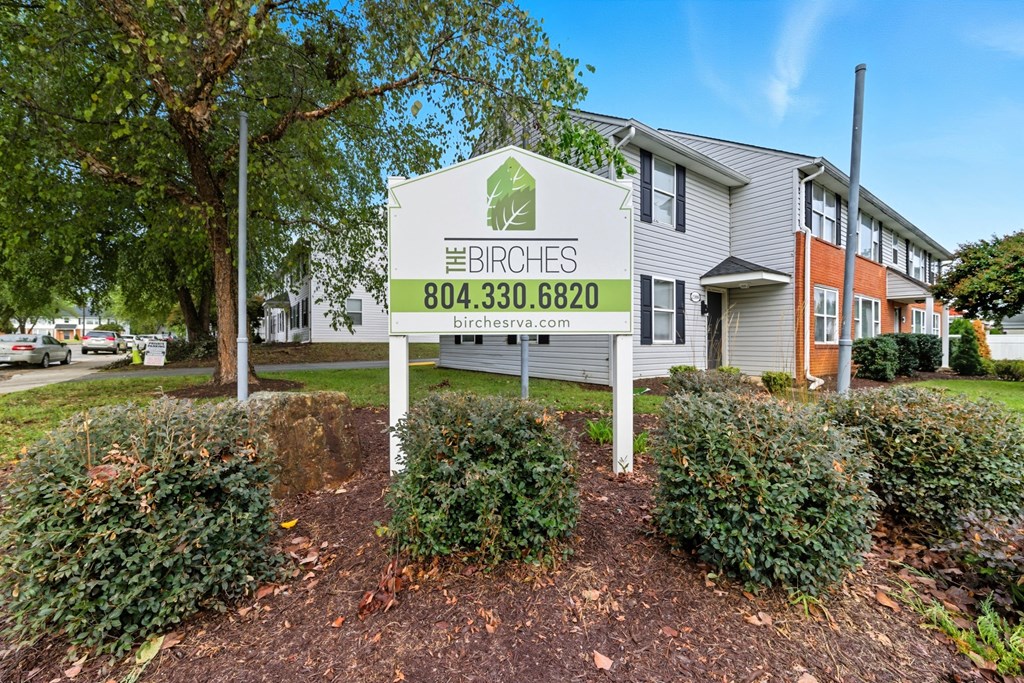 A sign for Birches apartments with a phone number on it.