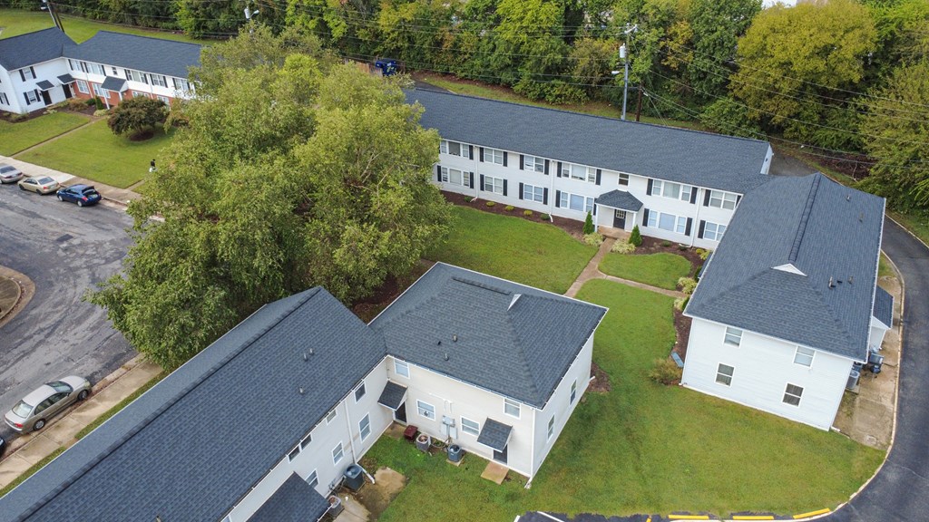A white building with a black roof is surrounded by a green lawn.