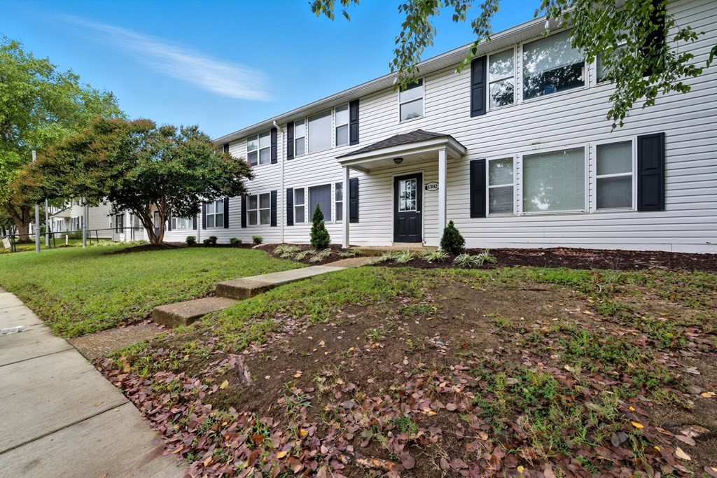 A residential building with a black front door and a small front yard.