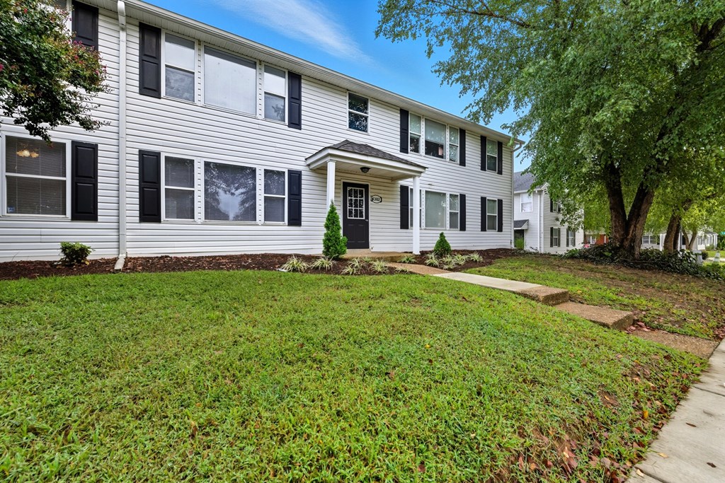 A white house with a green lawn in front.