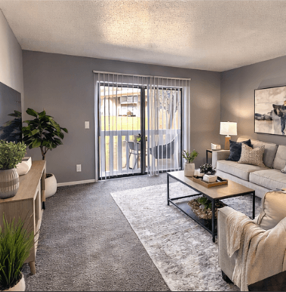 A living room with a grey carpet and a glass coffee table.