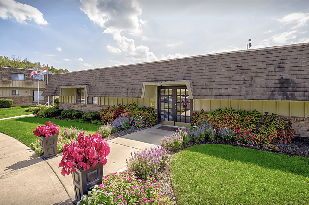a sidewalk in front of a building with flowers and plants