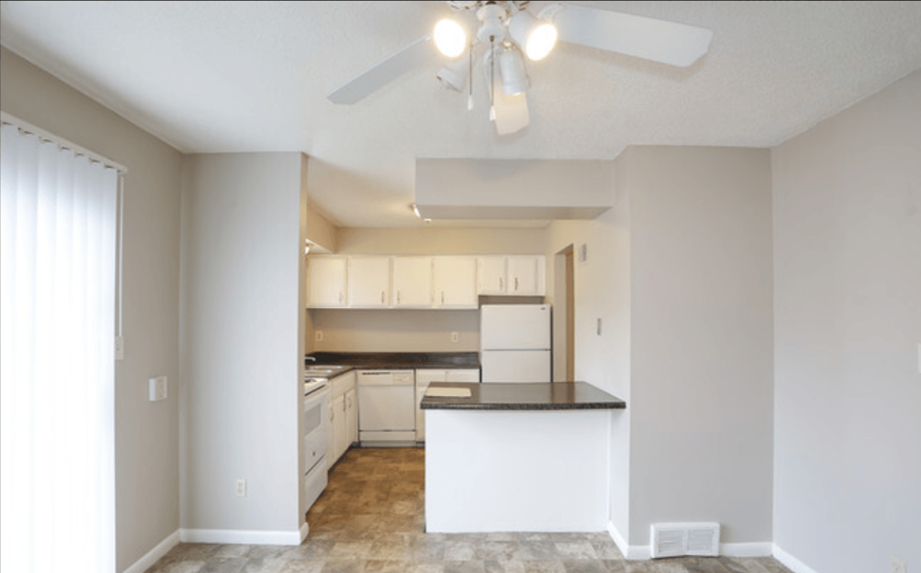 an empty kitchen with white cabinets and a ceiling fan