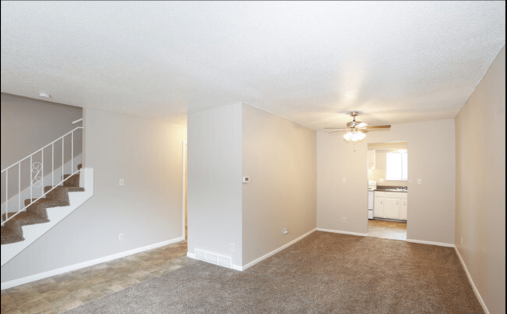 the living room of an empty house with a ceiling fan