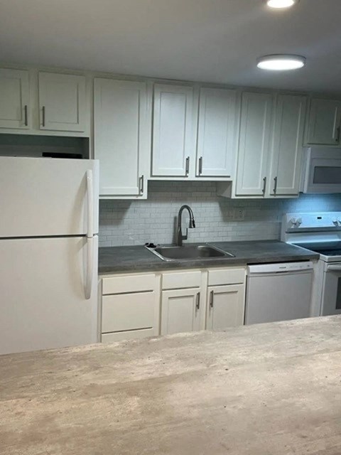 a kitchen with white cabinets and a sink and a refrigerator