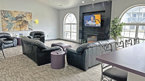 A living room with a television and black leather furniture.