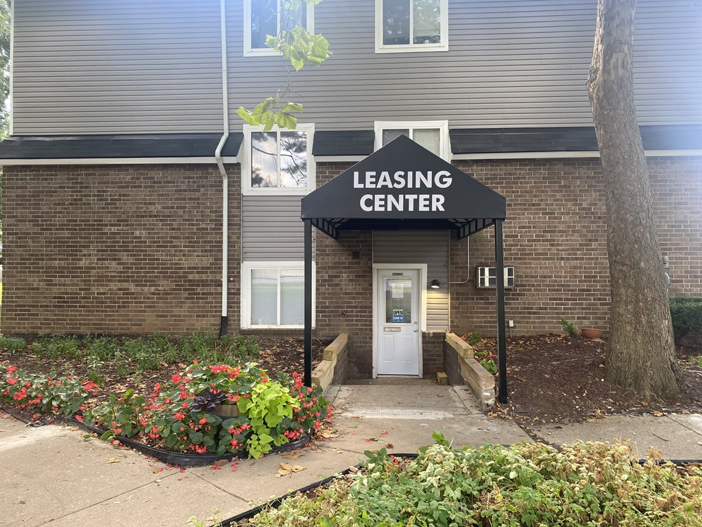 A leasing center is located in a brick building with a white door and a black awning.
