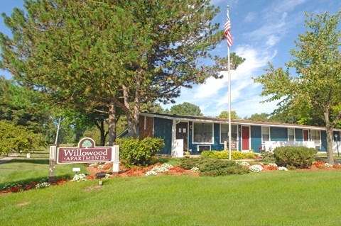A sign that says Willowood Apartments is in front of a building.