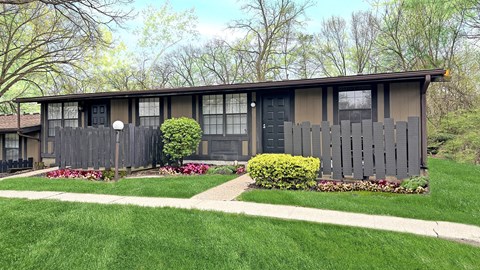 A house with a grey fence and a green lawn.