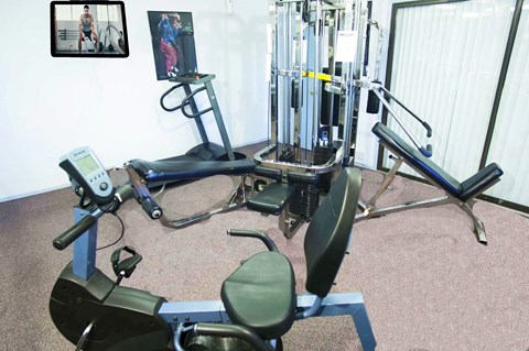 A gym room with a rowing machine, a leg press machine, and a weight machine.