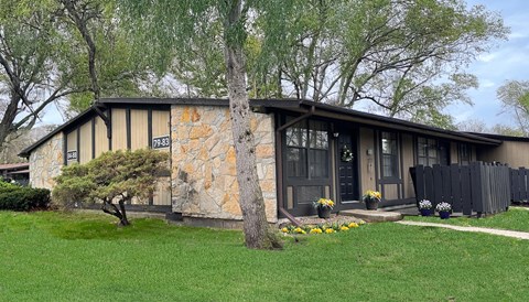 A house with a stone wall and a black fence.