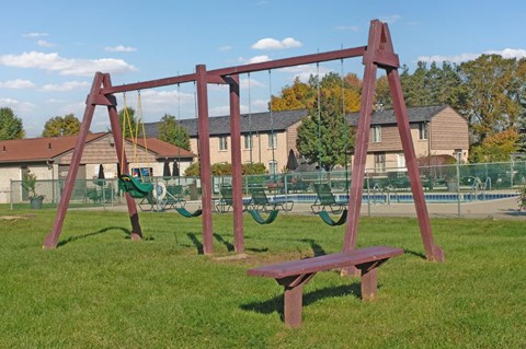 A swing set with a red frame and a bench in the foreground.