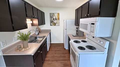 A kitchen with black cabinets and a white stove top oven.