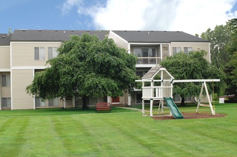 A playground with a slide and a swing set in front of a building.