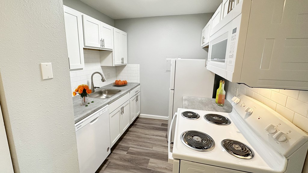 A white kitchen with a stove and a microwave.