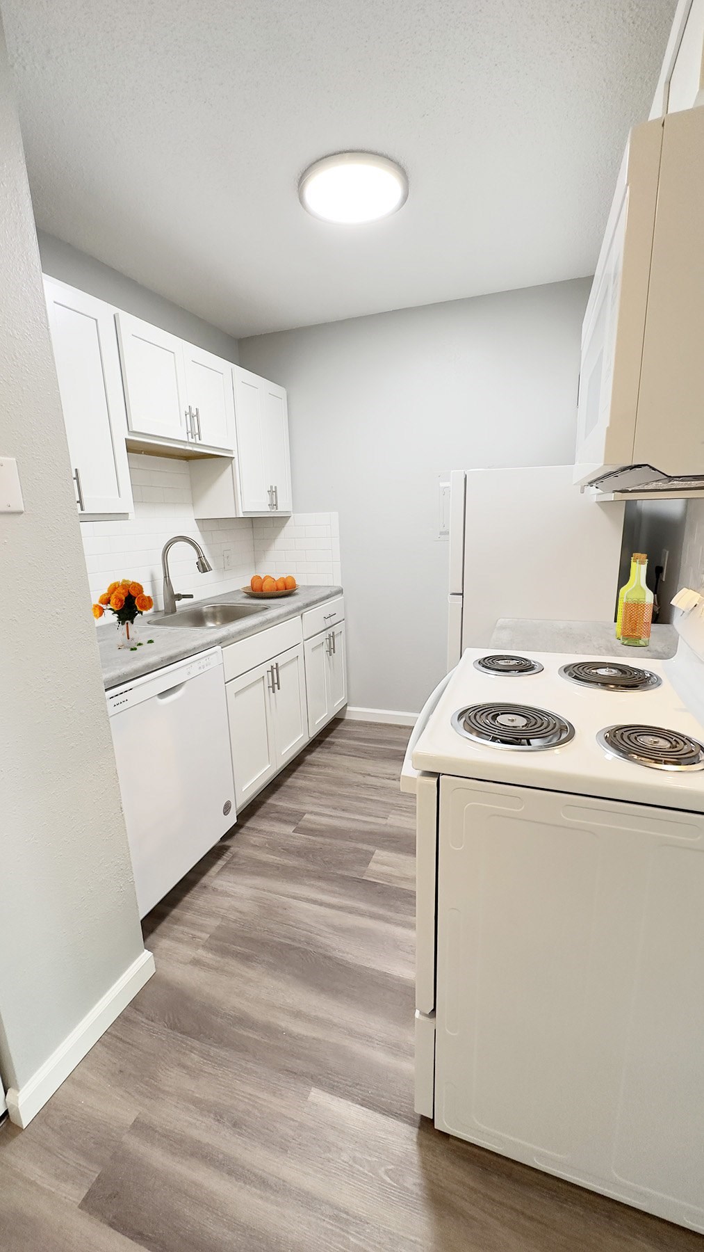 A kitchen with white cabinets and a white stove top oven.