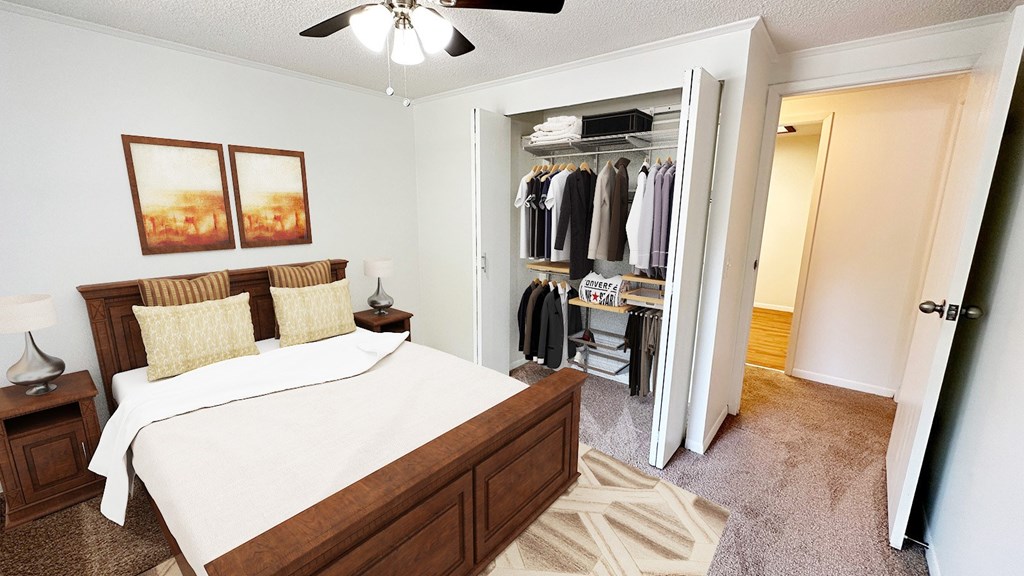 A bedroom with a large bed and a closet with clothes hanging.