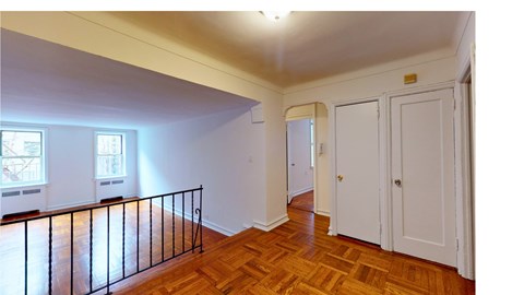 A room with a balcony and wooden floors.