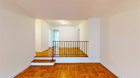 A room with wooden floors and a staircase leading to a balcony.