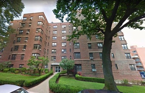 A large brick apartment building with a tree in front.