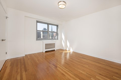 A room with wooden floors and a window overlooking a cityscape.