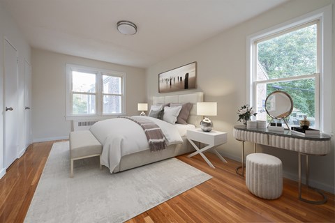 A well-lit bedroom with a large bed and a desk with a chair.