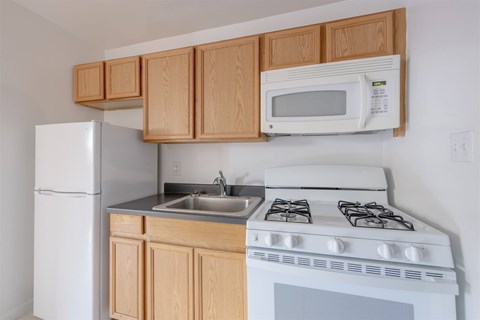 A white stove and sink in a kitchen with wooden cabinets.