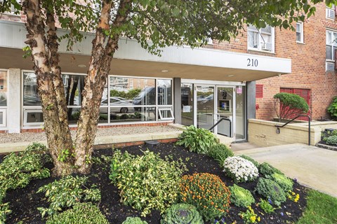 A building with the number 210 on it has a landscaped garden in front.