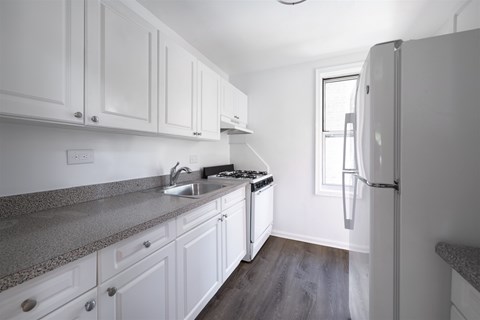 A kitchen with white cabinets and a granite countertop.