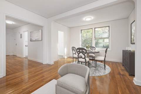 A living room with a grey armchair and a table with chairs.