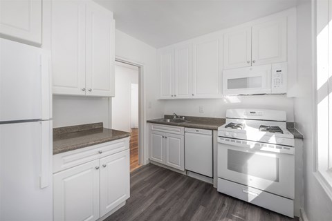 A kitchen with white cabinets and appliances.