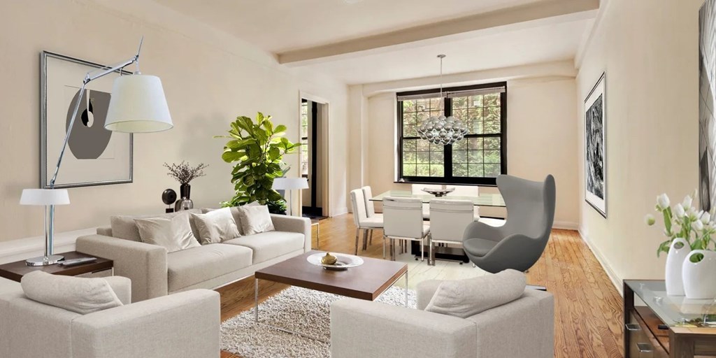 A living room with a grey sofa, a white armchair, a wooden coffee table, and a large window with a view of a garden.at London Terrace Gardens, New York, NY