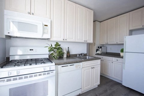 A white kitchen with a stove, microwave, and refrigerator.