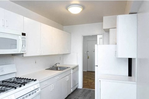 A white kitchen with a stove, microwave, and refrigerator.