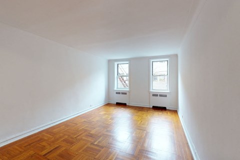 A room with wooden floors and two windows.