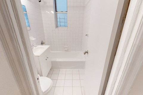 A white bathroom with a tub, toilet, and sink.