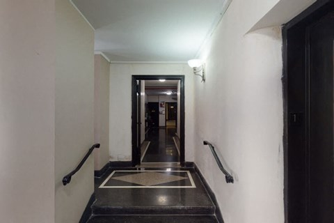 A hallway with a black door and a black handrail.