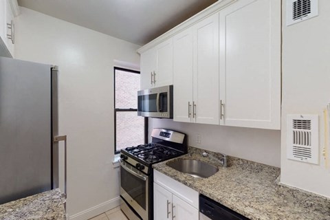 A kitchen with granite countertops and white cabinets.