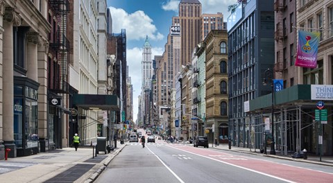 A city street with buildings on both sides and a clear blue sky.
