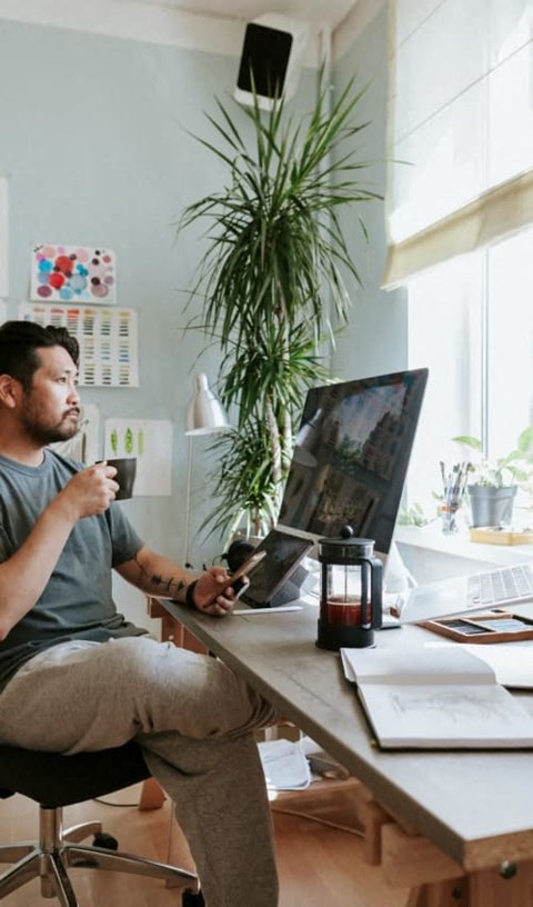A man is sitting at a desk with a cup in his hand.