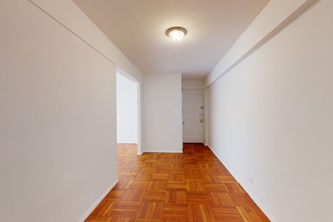 A long hallway with a wooden floor and white walls.