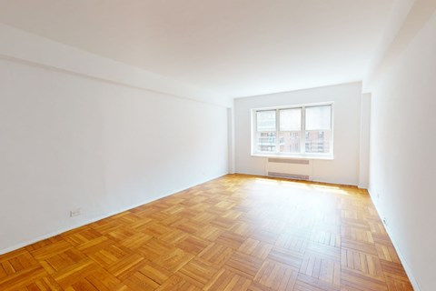 A room with a window and wooden flooring.