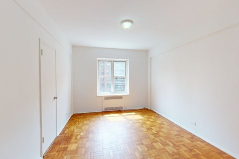 A room with a window and a wooden floor.