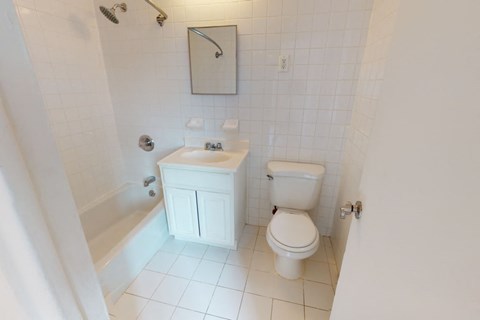 A white toilet sits next to a white bathtub in a small bathroom.
