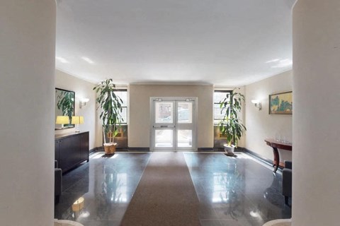 A spacious room with a large rug in the middle and a door at the end.